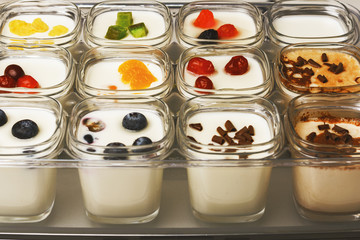 Closeup of homemade yogurt in glass jars with different types of toppings. Healthy food