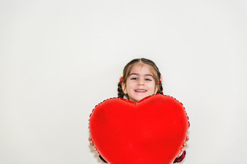 Little girl playing with red heart shaped balloon.