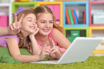 Portrait of two cute little girls using laptop