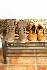 Brown leather autumn boots stand on the shelf in the hallway of the house near the white wall