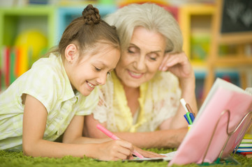 Grandmother with cute little girl doing homework together