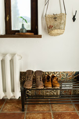 Brown leather autumn boots stand on the shelf in the hallway of the house near the white wall