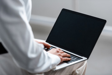 cropped view of woman using laptop with blank screen
