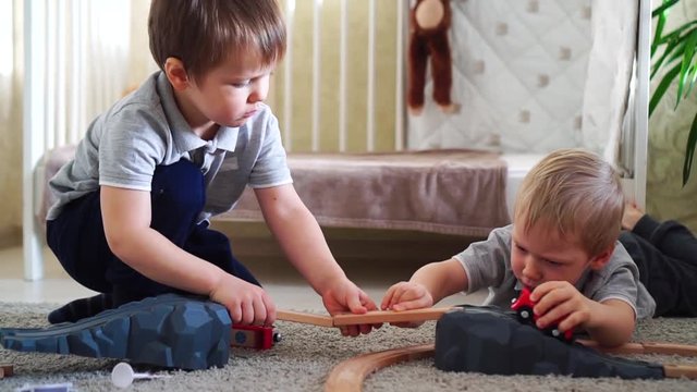 Children play with wooden train and build toy railroad at home