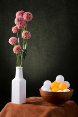 Still life with a flower branch in a white vase with colorful balls