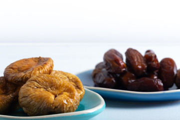 Dried figs and dates on a platter on a white background
