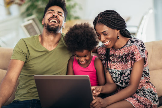 African American Family Using Laptop In The Living Room.