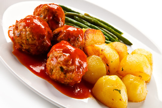 Roast meatballs with potatoes and green bean on white background