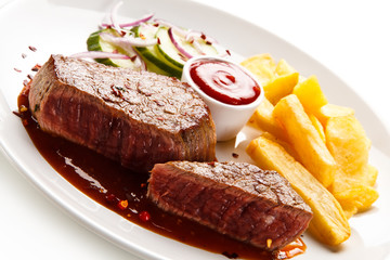 Grilled beefsteak with french fries and vegetable salad on white background