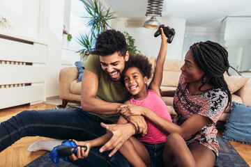 Smiling family sitting on the couch together playing video games