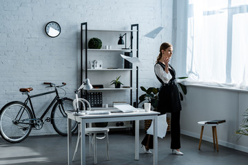 businesswoman in formal wear throwing documents in air at workplace