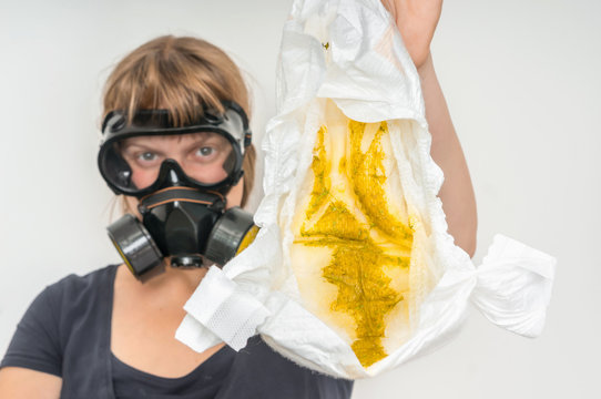 Mother With Gas Mask Changing Smelly Diaper