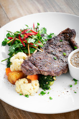 premium beef steak with steamed vegetables meal on white plate