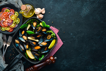 Fried mussels in a frying pan. Top view. Free space for your text. On the old background.