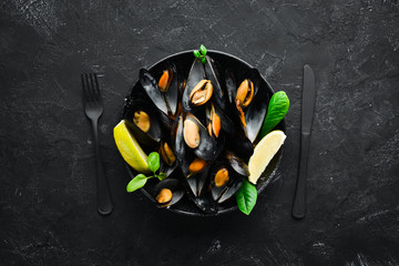 Boiled mussels with spices in a plate. Top view. Free space for your text. On the old background.