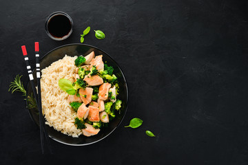 Rice with chicken fillet and vegetables. Top view. On a black background. Free copy space.