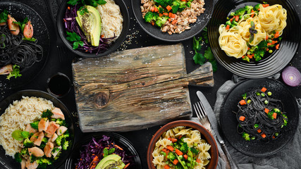 A set of food and dishes. Pasta, rice, risotto, salad. On a black background. Free copy space.