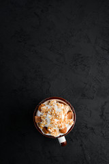 Obraz na płótnie Canvas Cappuccino with milk and nuts and marshmallow. On a black stone background. Top view. Free copy space.