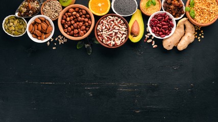 Various superfoods. Dried fruits, nuts, beans, fruits and vegetables. On a black wooden background. Top view. Free copy space.