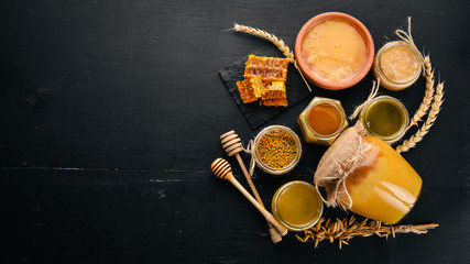 A set of honey and bee products. Honey in honeycomb. On a black wooden background. Free space for...