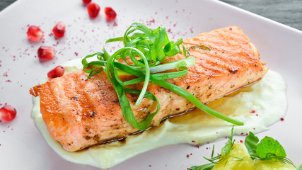 Baked salmon fillet with vegetables on a plate. On a wooden background. Top view. Free space for your text.