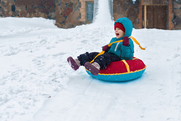 happy child. little boy in winter ride on a sled from the mountain. Kid long and happy smiles and have fun.