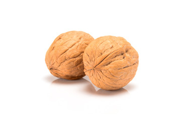 Two unbroken walnuts, close up macro, isolated on a white background.