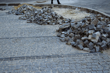 heaps of paving stones lie on the road, laying stones, unfinished work. road pedestrian area