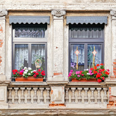 windows with geranium flower pots, old house facade detail