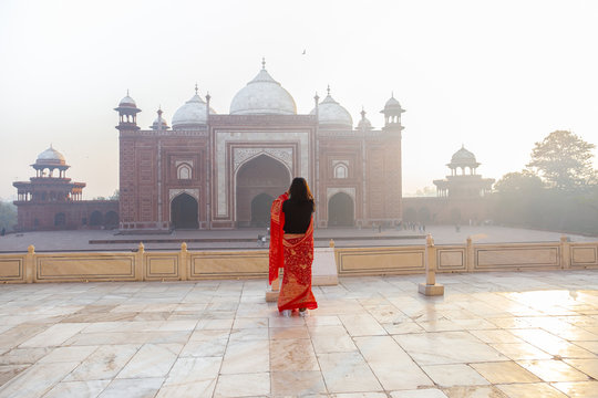 Indian woman in sari taking photo Taj Mahal in the morning.