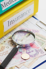 Clean insurance form, magnifying glass and Ukrainian money, blurred background