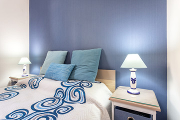 Bed in a modern bedroom with lamps and pillows.