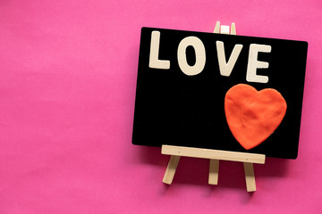 word LOVE and red heart in Blackboard on pink background, Love icon, valentine's day, relationships concept with copy space
