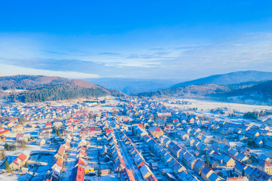 Croatia, Delnice, Gorski kotar, panoramic view of town center from drone in winter, mountain landscape in background, houses covered with snow 