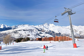 Fototapeta na wymiar ski slopes in french alps resort and chair lift under blue sky