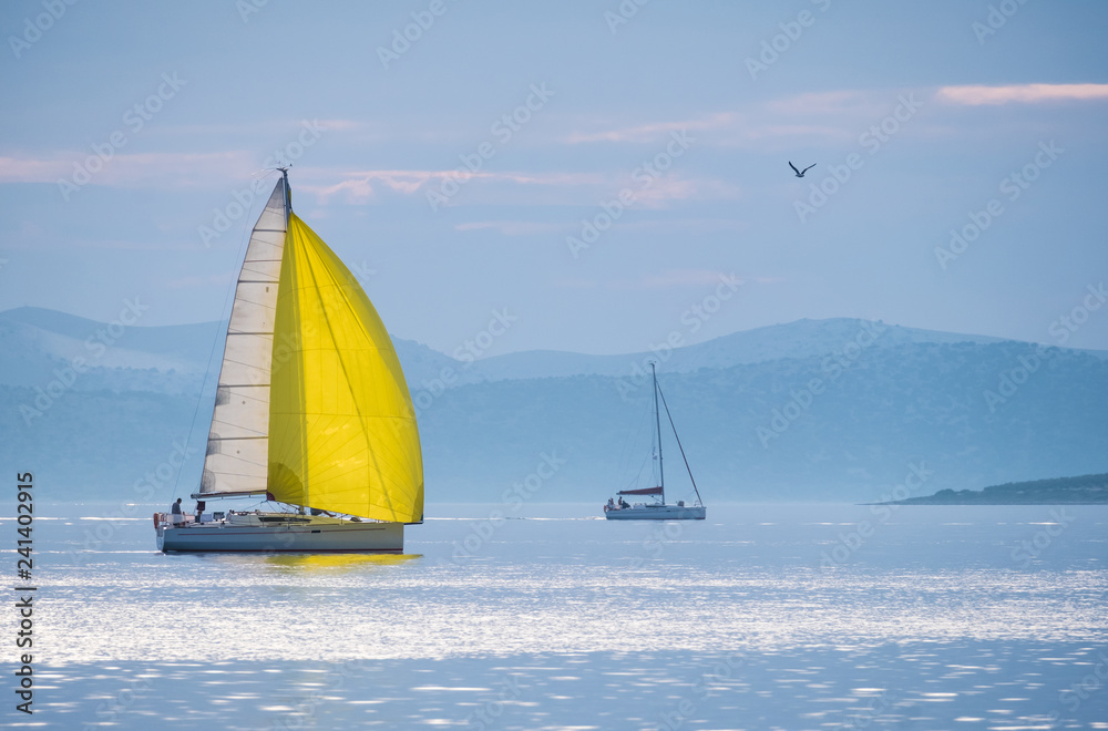 Wall mural sailing boat with yellow spinnaker sailing on calm sea