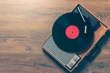 Retro Gramophone with a vinyl record on wooden table, top view and copy space,vintage style with...