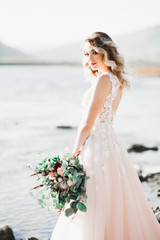 Fototapeta na wymiar Beautiful fashion bride in wedding dress posing near river