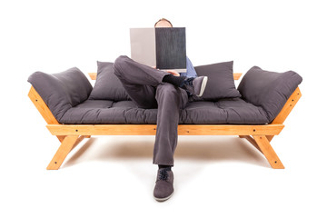 Businessman sitting on gray sofa and reading.