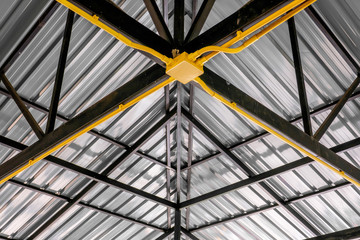 Fototapeta premium The yellow electric wire pipe on the ceiling in the house with the metal roof.