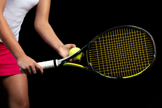 Young woman on a tennis practice. Beginner player holding a racket, learning basic skills. Portrait on black background.
