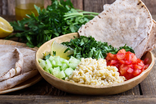 Tabbouleh salad bowl with bulgur, fresh parsley and vegetables served with pita bread