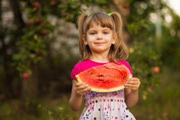 Happy child girl eats watermelon in summer. Healthy eating concept