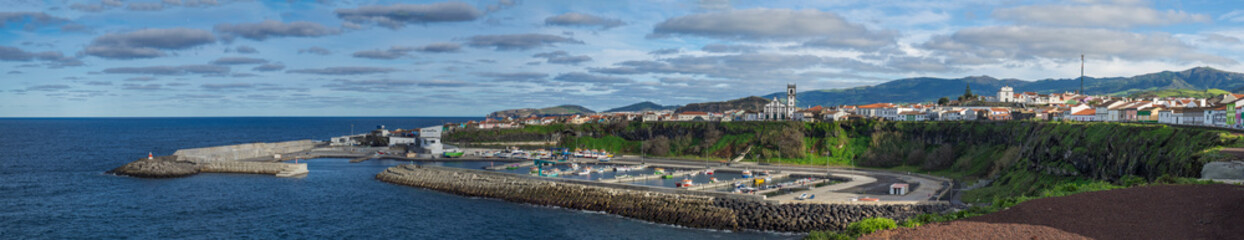 Fototapeta na wymiar Panoramic View of colorful quay and port of village Rabo de Peixe with boats, church and lighthouse in Sao Miguel, the largest of the Azores Islands, Portugal. Sunny cloudy day