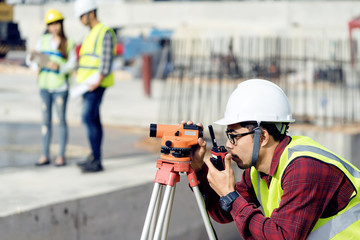 surveyor engineer with theodolite at construction site during surveying work.engineer and architect working at construction site with blueprint - obrazy, fototapety, plakaty