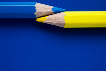 Macro photo of yellow and blue pencil on blue paper, Ukraine flag colors