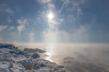 Vapor trails over water on a freezing cold sunny day