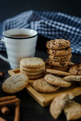 Two cups of tea and various cookies on dark wooden background