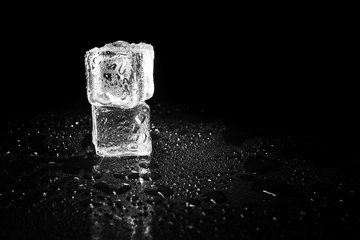 ice cubes reflection on black table background.