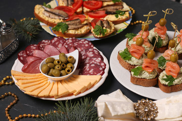 Fototapeta na wymiar Appetizer on a festive table - canapes with salmon, sandwiches with sprats and sliced cheese and sausage